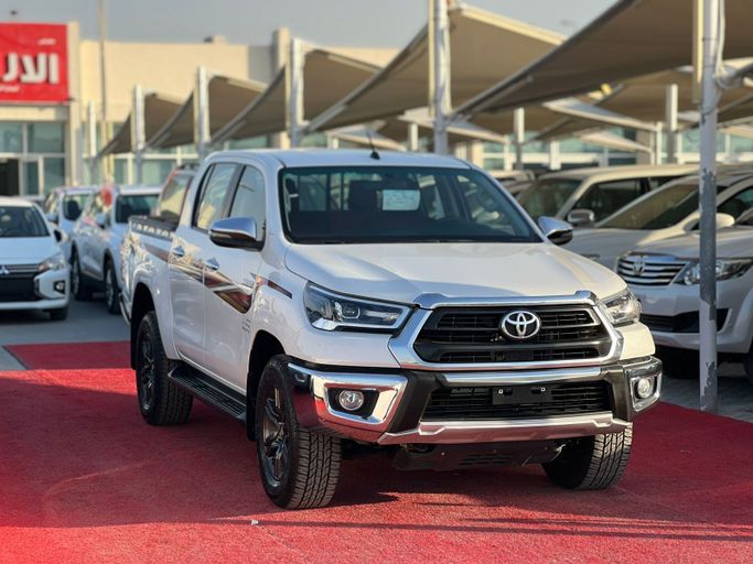 Подержанный Toyota Hilux VIII Рестайлинг, 2.7 л, 2025 в Шардже от Al Aram Cars Белый цвет. GCC | AUTO.AE